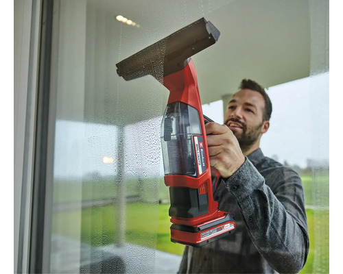 Mann reinigt Fenster mit einem Akku-Fenstersauger von Einhell