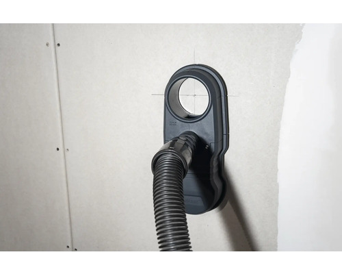 Staubsaugeranschlussdose mit angeschlossenem Staubsaugerschlauch an einer Wand