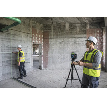 Baustelle mit Bauarbeiter, der einen Linienlaser auf einem Stativ bedient