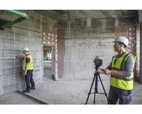 Baustelle mit Bauarbeiter, der einen Linienlaser auf einem Stativ bedient