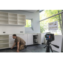 Handwerker montiert Küchenschränke mit einem Linienlaser