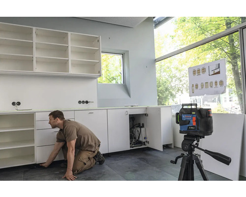 Handwerker montiert Küchenschränke mit einem Linienlaser