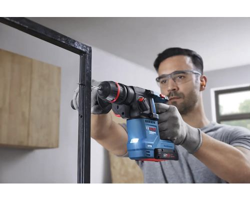 Mann bohrt mit einem Bohrhammer ein Loch in einen Metallrahmen