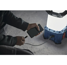 Ein Mobiltelefon wird an eine akkubetriebene Arbeitsleuchte angeschlossen, um es aufzuladen.