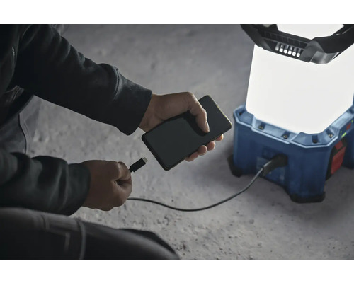 Ein Mobiltelefon wird an eine akkubetriebene Arbeitsleuchte angeschlossen, um es aufzuladen.