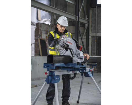 Ein Arbeiter in Arbeitskleidung verwendet eine Metallkreissäge von Bosch, um ein Metallrohr zu schneiden.