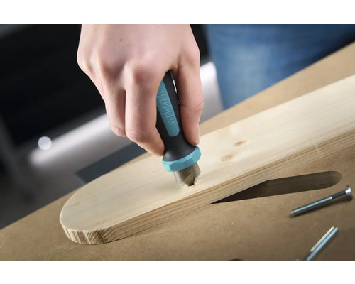 Eine Hand senkt einen Senker der Marke Wolfcraft in ein Holzbrett, um eine Schraube zu versenken.