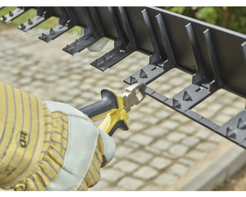 Gartengestaltung mit Rasenkante aus Kunststoff und einer Zange.