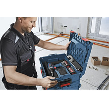 Handwerker öffnet einen Werkzeugkoffer mit einem Akkuschrauber