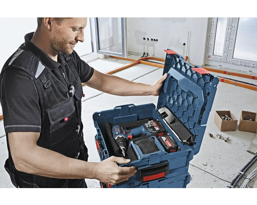 Handwerker öffnet einen Werkzeugkoffer mit einem Akkuschrauber