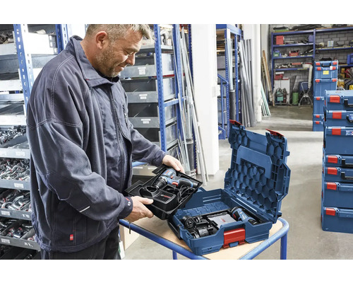 Mann packt Akkuschrauber in Werkzeugkoffer im Lagerregal