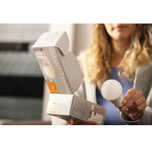 Frau hält eine SMART+ Glühbirne und deren Verpackung.