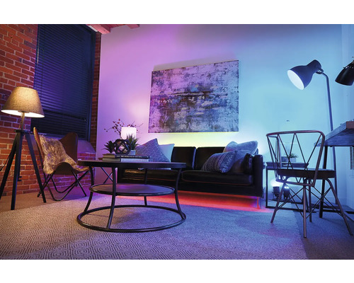 Wohnzimmer mit Sofa, Tisch, Stehlampe und farbiger Beleuchtung für eine angenehme Atmosphäre