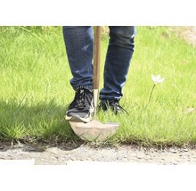 Person, die einen Spaten im Gras benutzt.