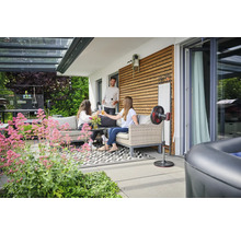 Terrasse mit Loungemöbeln, Stehventilator und entspannten Personen