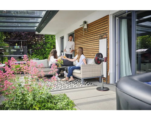 Terrasse mit Loungemöbeln, Stehventilator und entspannten Personen