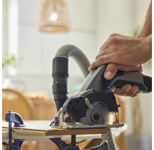 Mann sägt Holz mit einer Tauchsäge mit Staubabsaugung