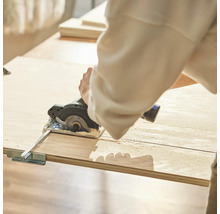 Person sägt Holzbrett mit Kreissäge