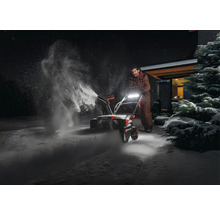 Eine Person benutzt eine Schneefräse, um Schnee zu räumen.