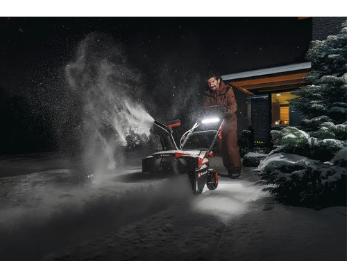 Eine Person benutzt eine Schneefräse, um Schnee zu räumen.