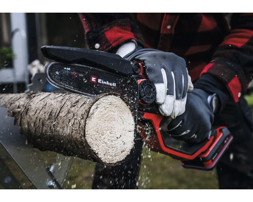 Ein Mann sägt einen Holzstamm mit einer Einhell Kettensäge.