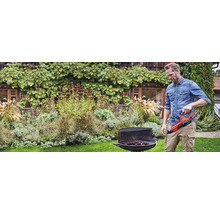 Mann zündet Grill mit Anzündkamin im Garten an