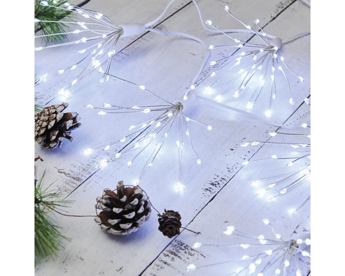 Lichterkette mit LED-Sternen und Tannenzapfen auf einem Holztisch