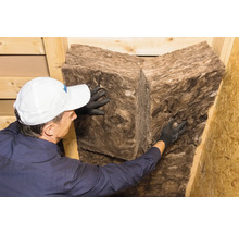 Eine Person, die Mineralwolle zur Wärmeisolierung anbringt.