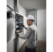 Elektriker arbeitet mit einem Akkuschrauber an einem Verteilerkasten.