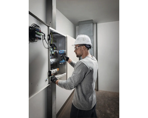 Elektriker arbeitet mit einem Akkuschrauber an einem Verteilerkasten.