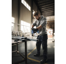 Ein Mann bohrt mit einem Akku-Bohrschrauber ein Loch in ein Metallprofil.