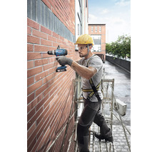 Handwerker bohrt mit einem Akku-Bohrschrauber ein Loch in eine Ziegelwand