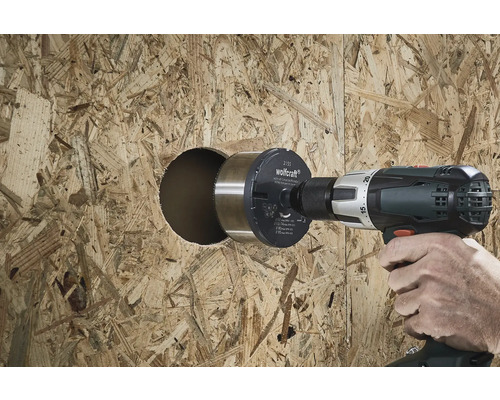 Eine Person bohrt mit einem Kreisschneider ein Loch in eine Holzplatte