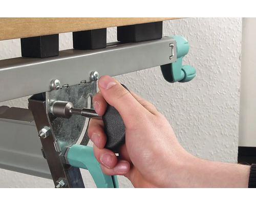 Eine Person befestigt einen Schrauben mit einem Schraubendreher an einem Metallbettrahmen.