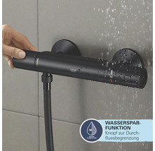 Schwarze Duscharmatur mit Wassersparfunktion und Hand, die den Knopf drückt.
