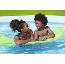 Zwei Kinder entspannen sich auf einer Luftmatratze im Schwimmbad.