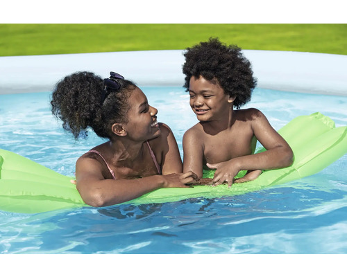 Zwei Kinder entspannen sich auf einer Luftmatratze im Schwimmbad.