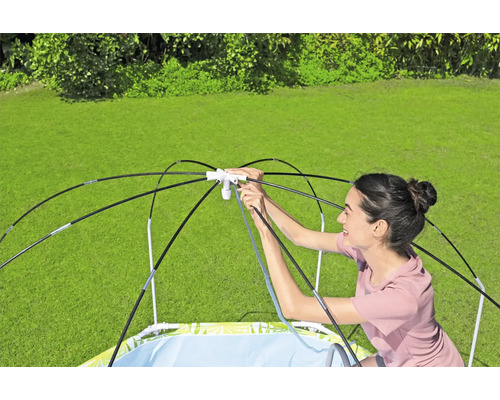 Frau baut Planschbecken mit Sonnenschutz im Garten auf