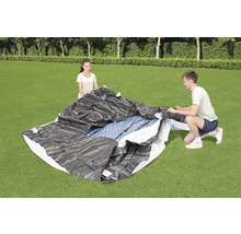 Personen bauen eine Poolabdeckung auf einer Rasenfläche auf.