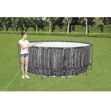 Frau befüllt einen Frame Pool im Garten mit einem Wasserschlauch.