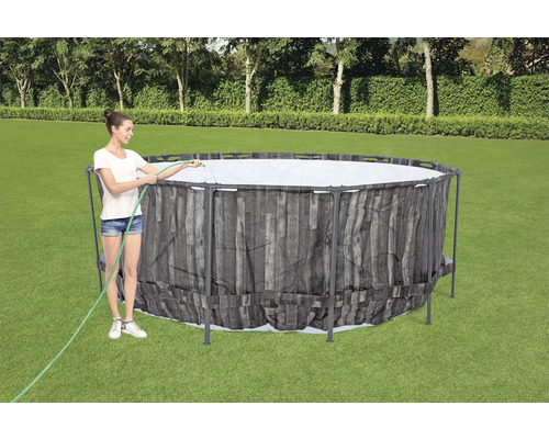 Frau befüllt einen Frame Pool im Garten mit einem Wasserschlauch.