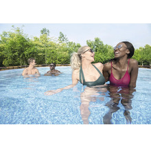 Szene mit fröhlichen Menschen, die in einem Schwimmbecken schwimmen, umgeben von Bäumen.