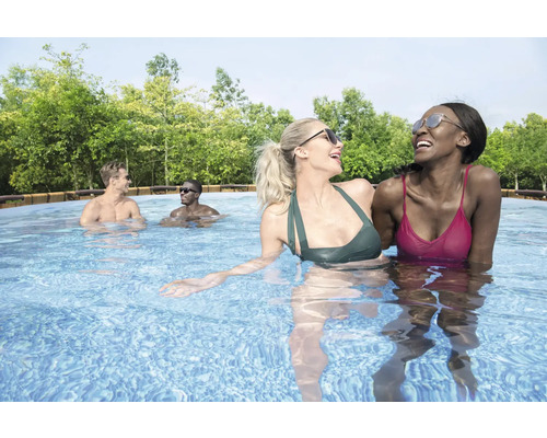 Szene mit fröhlichen Menschen, die in einem Schwimmbecken schwimmen, umgeben von Bäumen.