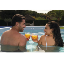 Ein Paar steht in einem Pool und stößt mit Getränken an