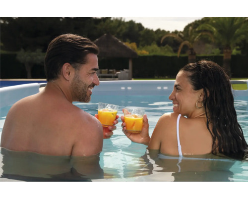Ein Paar steht in einem Pool und stößt mit Getränken an