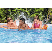 Drei Kinder spielen auf einer Luftmatratze im Schwimmbad.