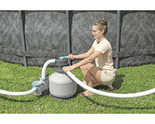 Frau bedient eine Sandfilteranlage für den Pool im Garten.