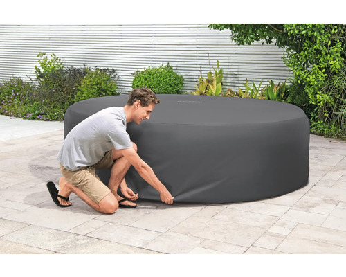 Abdeckung für einen Whirlpool im Außenbereich, die von einer Person befestigt wird.