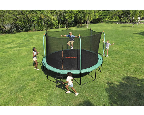 Trampolin mit Sicherheitsnetz im Garten mit spielenden Kindern