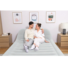Paar sitzt auf einem hellen Luftbett mit Kopfteil in einem hellen, modernen Schlafzimmer